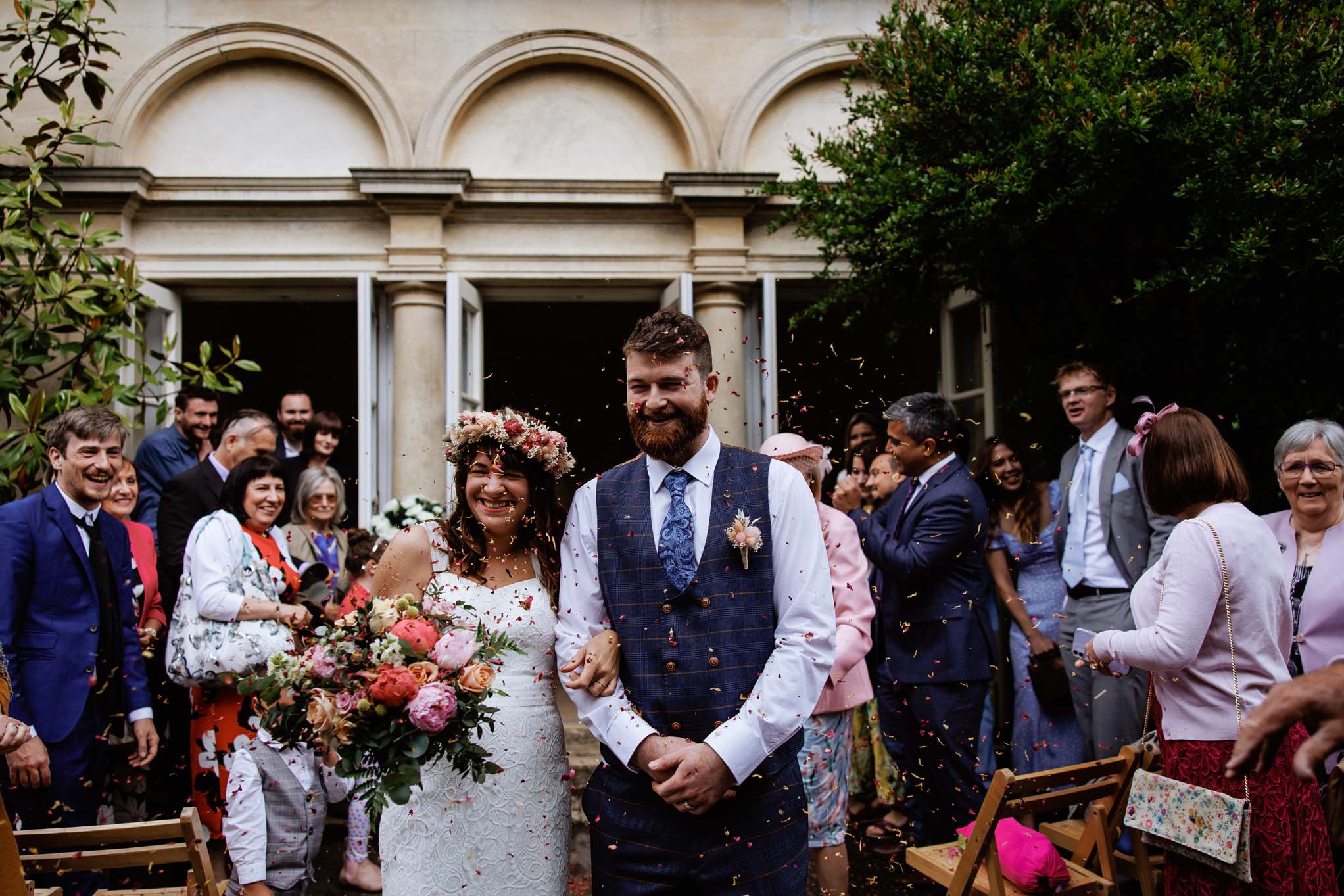 Confetti being thrown over wedding couple outside the Temple Of Minerva